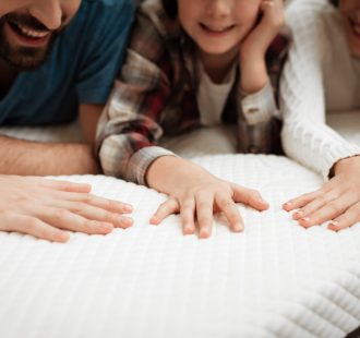Closeup Happy Family Touching Mattress in Store.